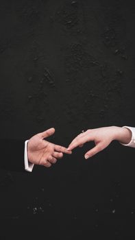 Close-up of two elegant hands reaching out against a dark background, symbolizing connection and elegance.