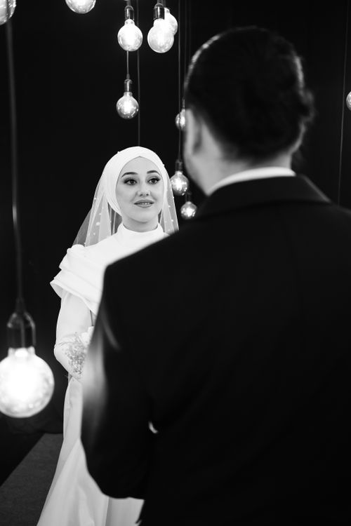 Free A black and white portrait of a bride and groom surrounded by hanging lights, capturing an elegant wedding moment. Stock Photo