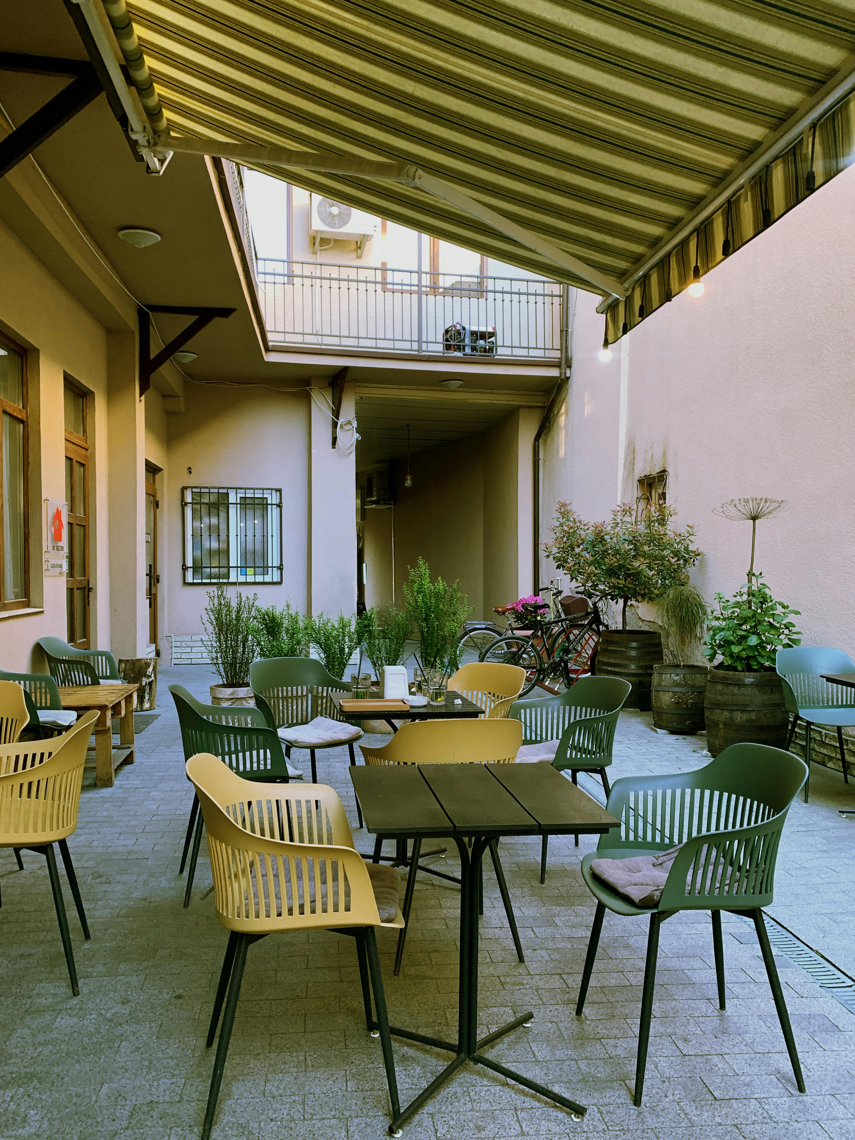 Gratuit Terasă fermecătoare într-o cafenea în aer liber, cu scaune și mese goale sub o copertină. Fotografie de stoc