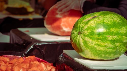 Free Whole and sliced watermelon displayed on cutting boards under sunlight. Stock Photo
