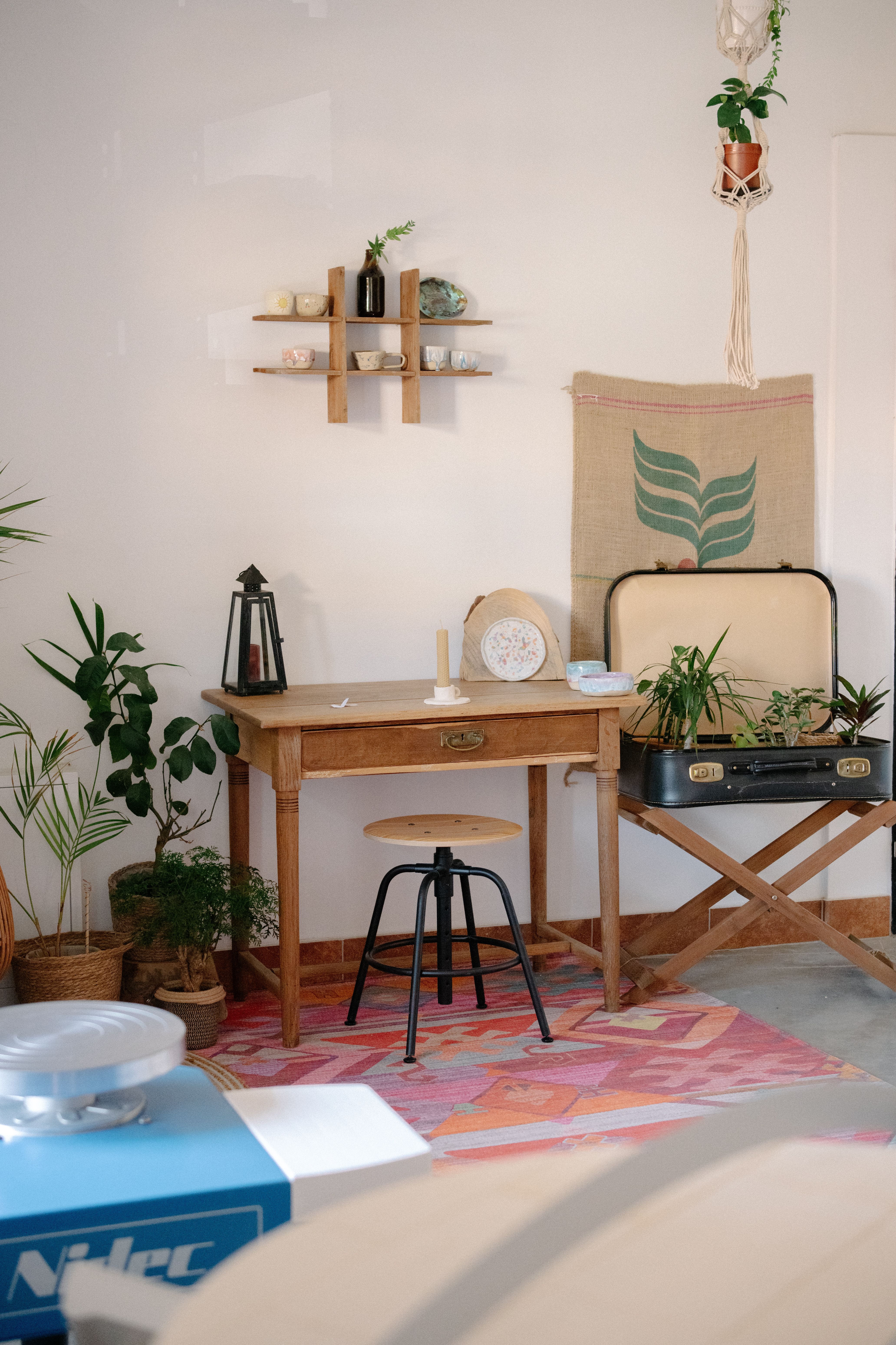 A cozy home office with vintage decor, featuring a wooden desk, plants, and wall art.