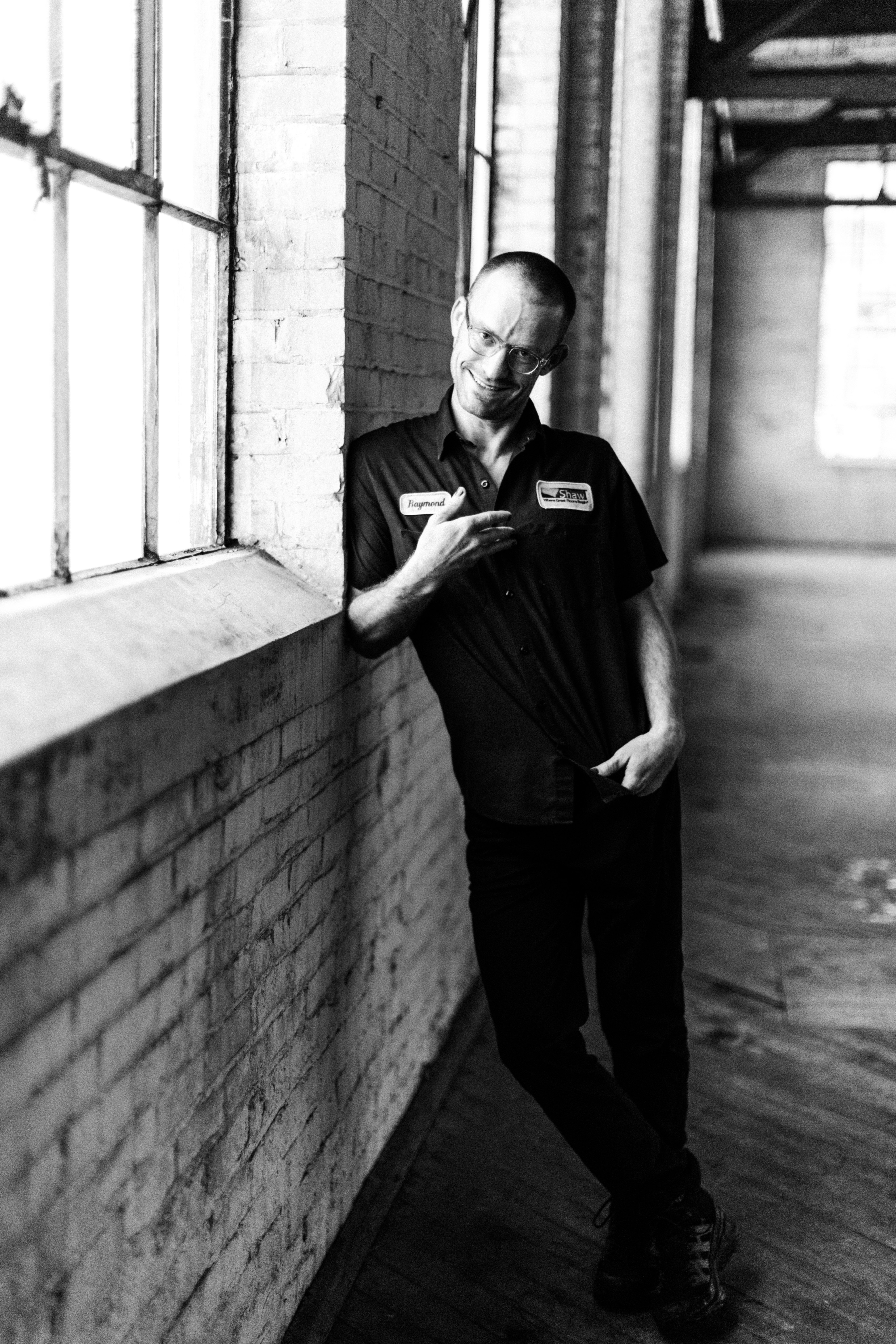 Stylish black and white portrait of a man leaning on a brick wall in an industrial interior.