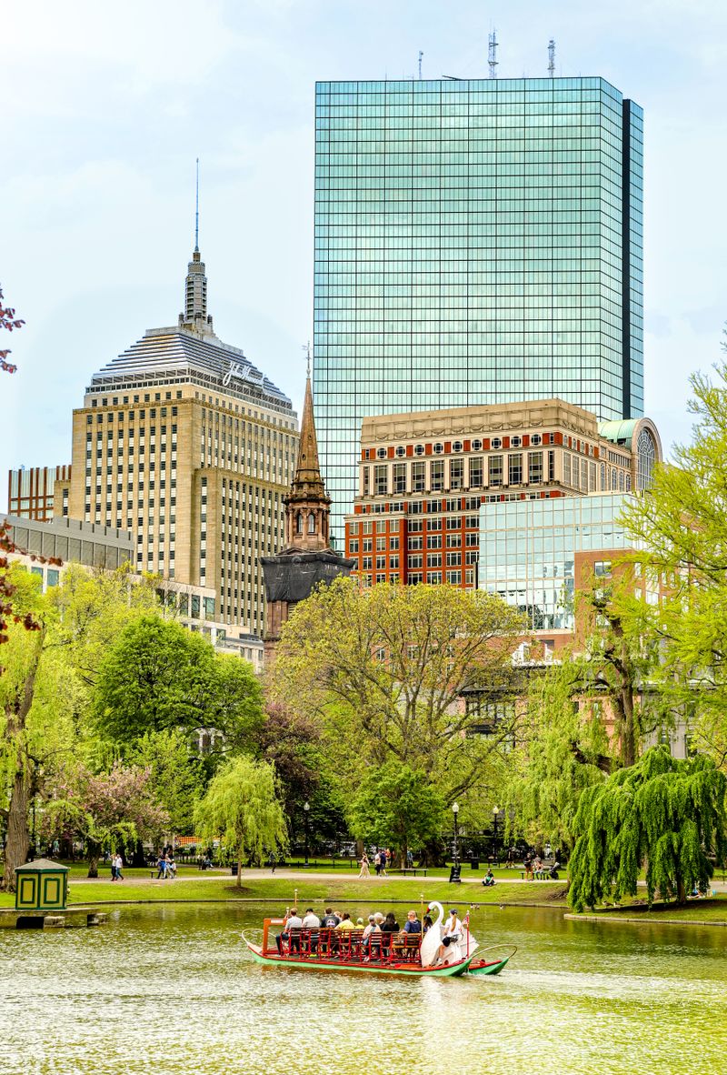 Swan boat on the lagoon of Boston Public Garden with the skyline behind