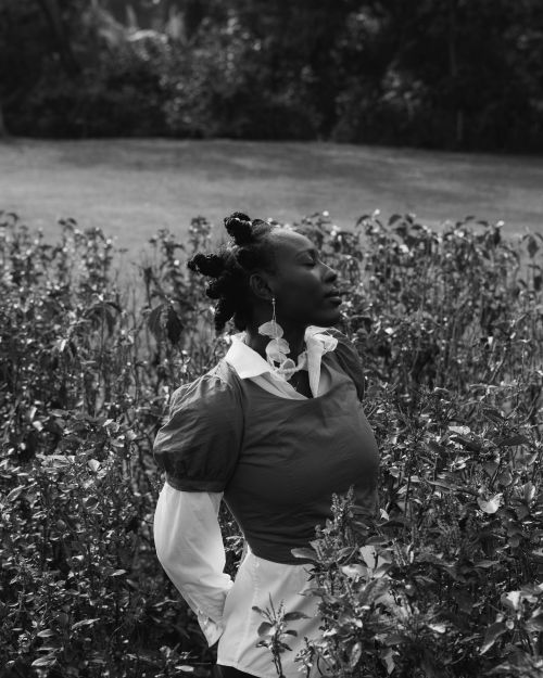 Free Black and white portrait of a woman standing in a lush garden, exuding elegance and serenity. Stock Photo