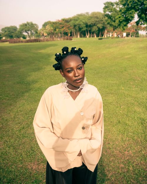 Free A stylish woman wearing a beige outfit stands gracefully in a sunlit park. Stock Photo