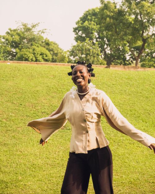 Free A cheerful woman with braided hair smiling and enjoying a sunny day in a green park. Stock Photo