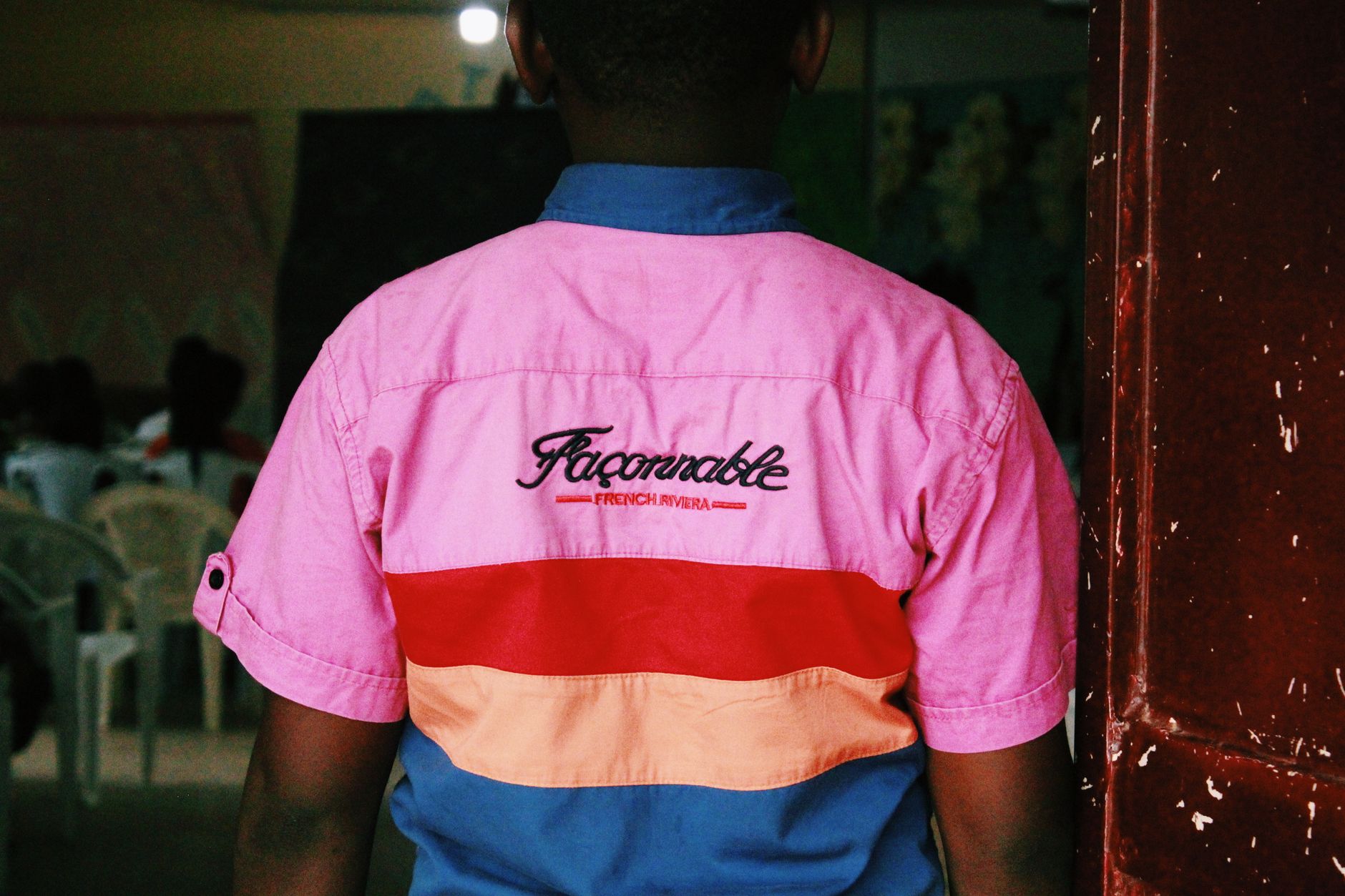 Back view of an African man wearing a colorful retro jacket indoors.