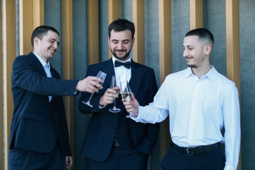 Free Three men in formal wear toasting with champagne glasses, celebrating outdoors. Stock Photo