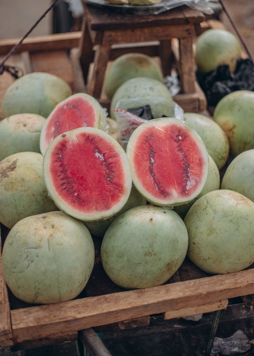 Free A rustic display of whole and sliced fresh watermelons at an outdoor market. Stock Photo