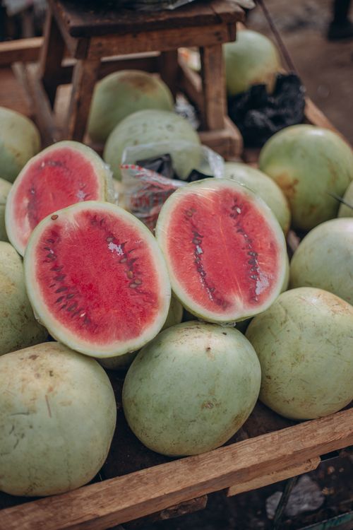 Free Pile of ripe watermelons with vibrant red interiors on a market stall, ready for sale. Stock Photo