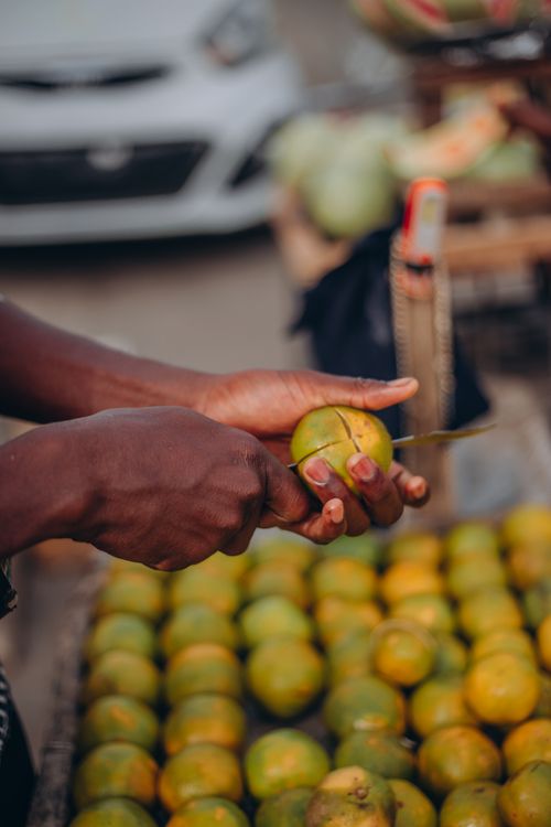 Free A person peeling fresh oranges at an open-air market, showcasing local produce. Stock Photo