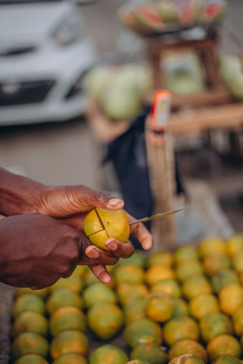 Free Close-up of hands cutting a citrus fruit at a bustling outdoor market. Vibrant and lively scene. Stock Photo
