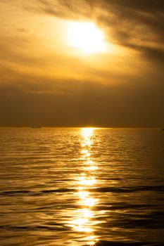 Serene ocean view at sunset with golden light reflecting on calm waters, creating a peaceful atmosphere.