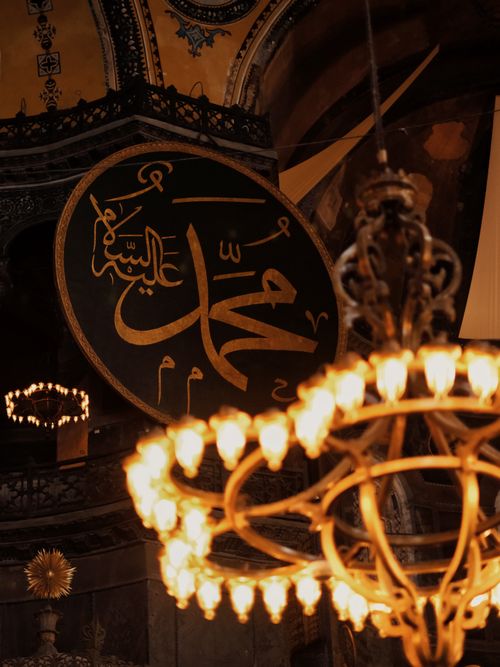 Free A chandelier lights up Arabic calligraphy in a historic mosque interior. Stock Photo