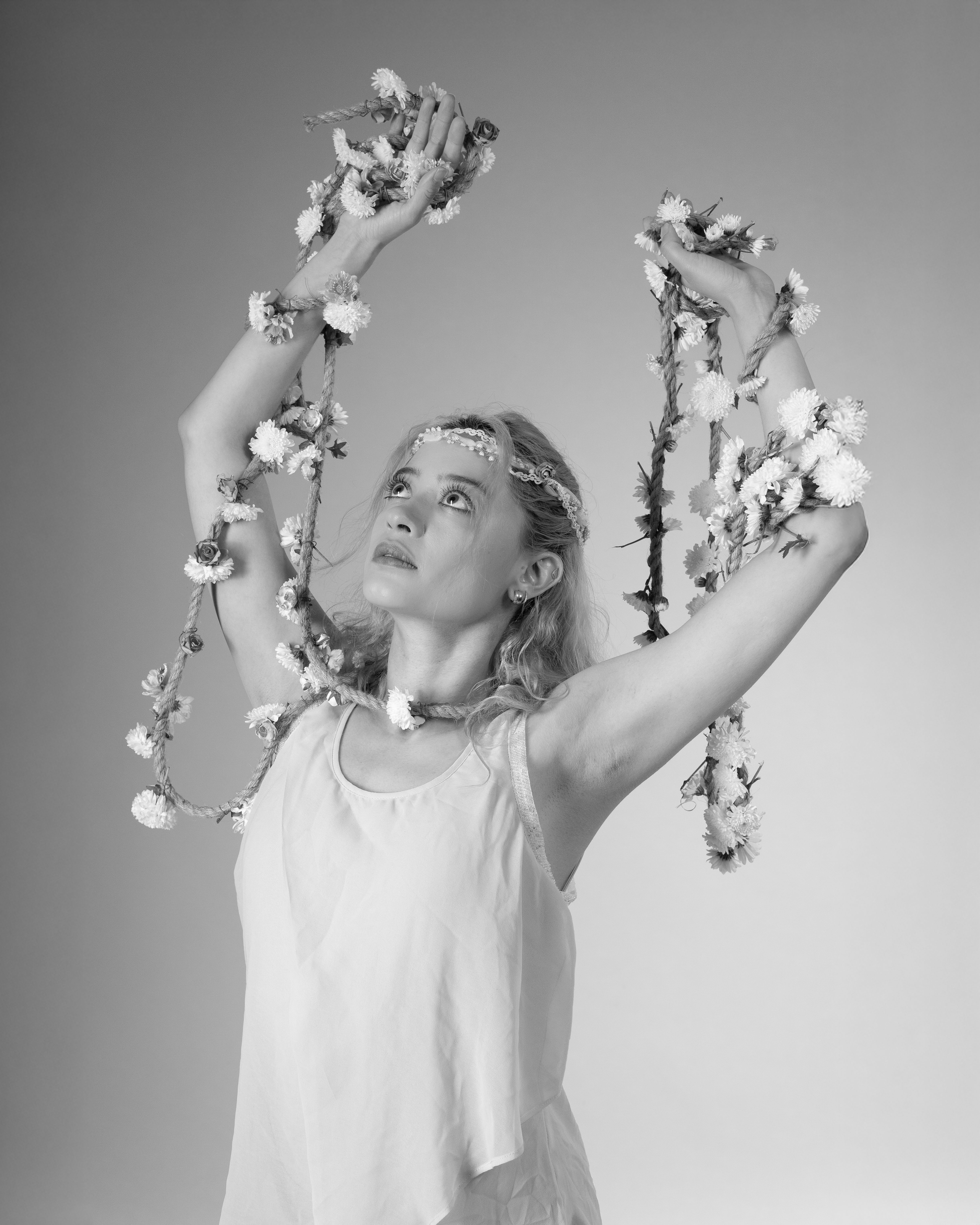 Ballet dancer poses gracefully with floral garland in monochrome. Artistic and elegant.