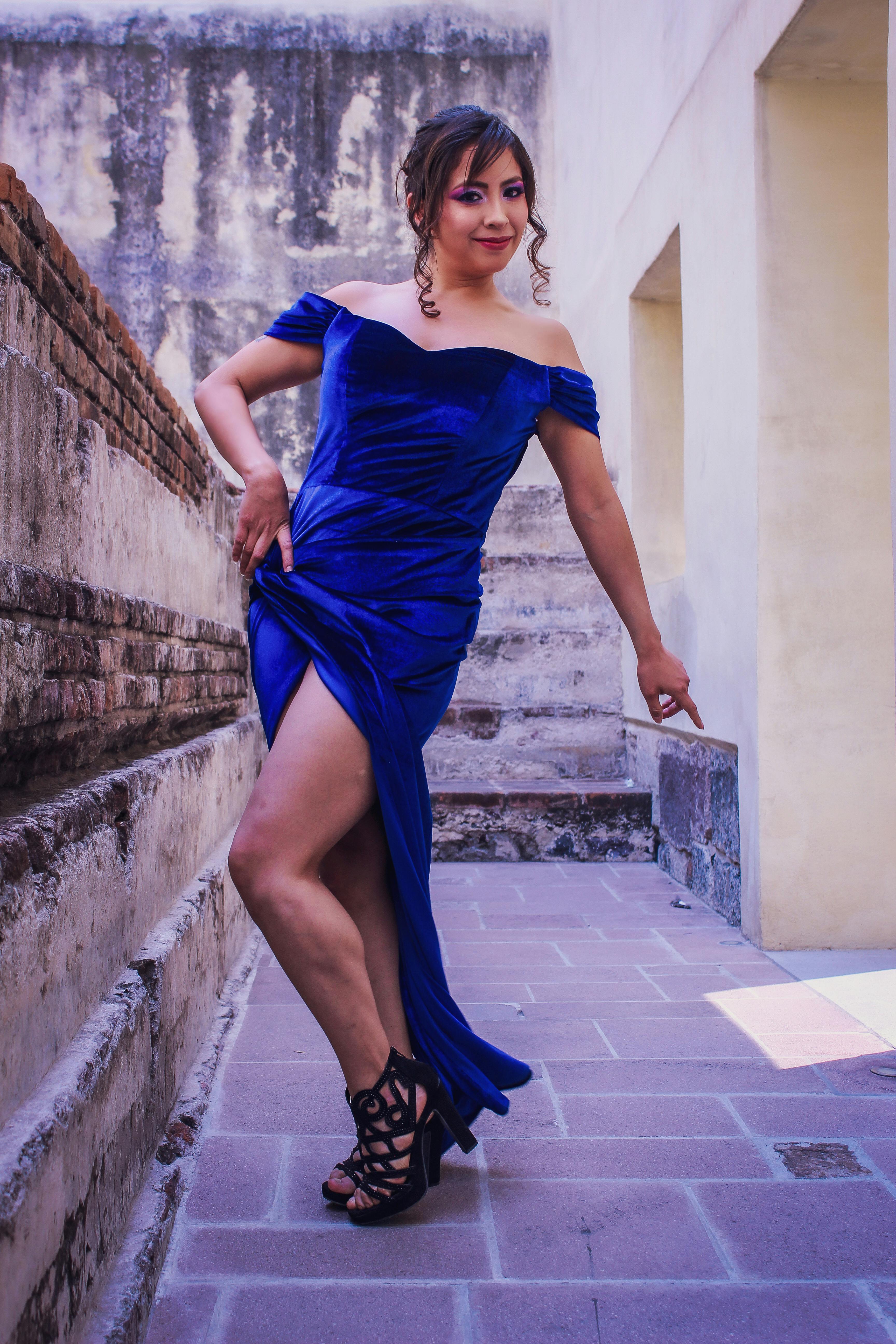 grátis Mulher estilosa em um vestido azul posa graciosamente em um cenário urbano histórico. Foto profissional