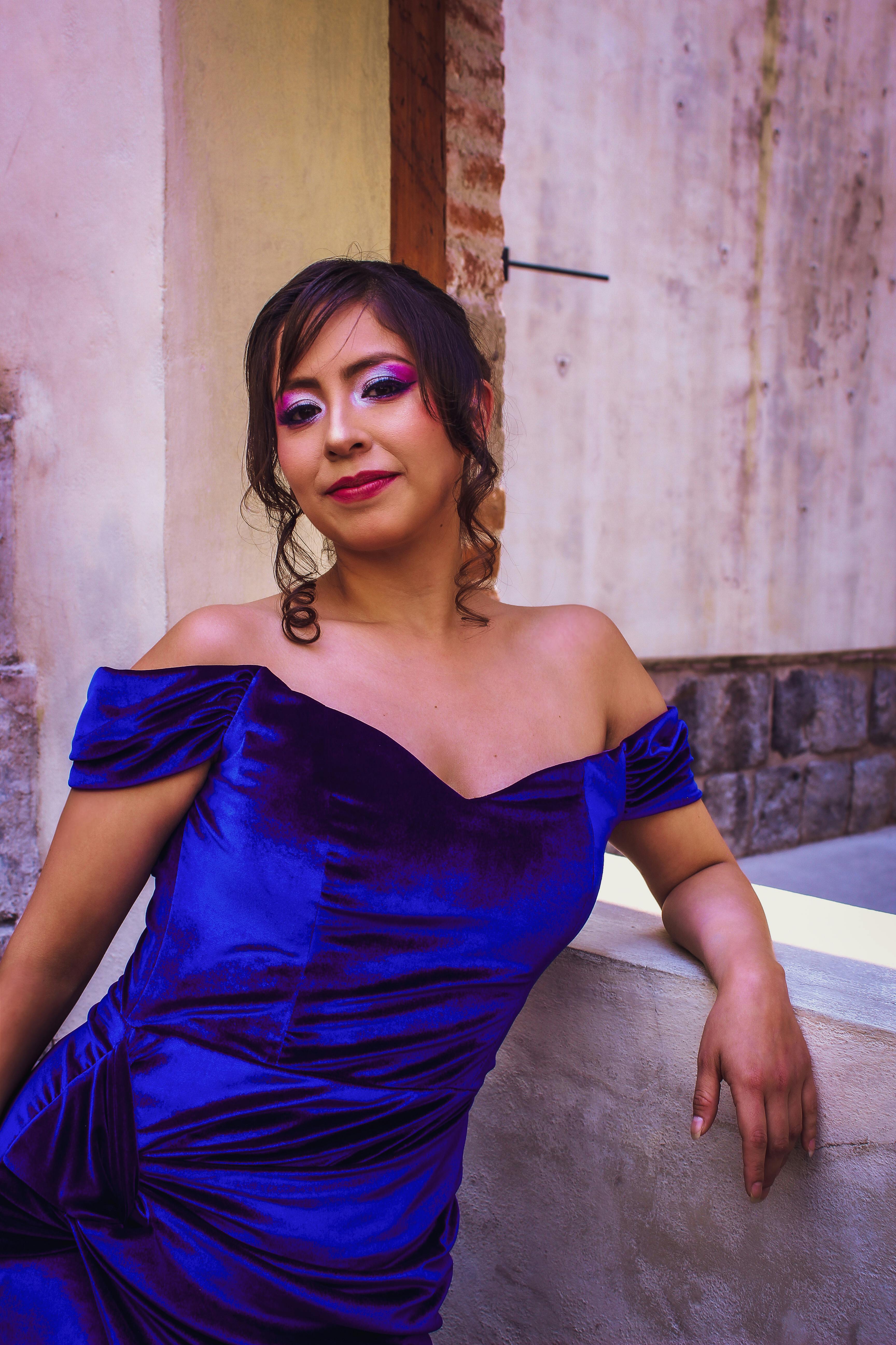 Free A woman poses elegantly in a royal blue dress against a rustic outdoor backdrop, showcasing fashion and style. Stock Photo