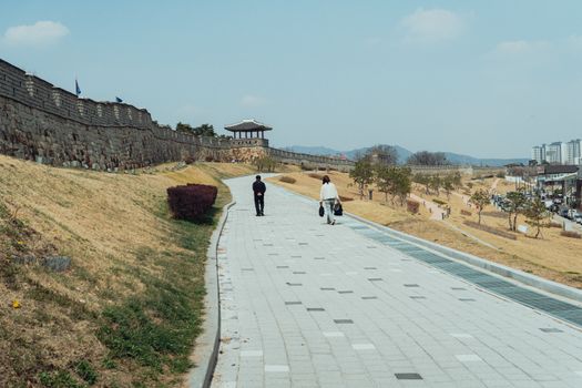 A serene walkway beside the historic Hwaseong Fortress in Seoul, capturing Korean architecture and culture.