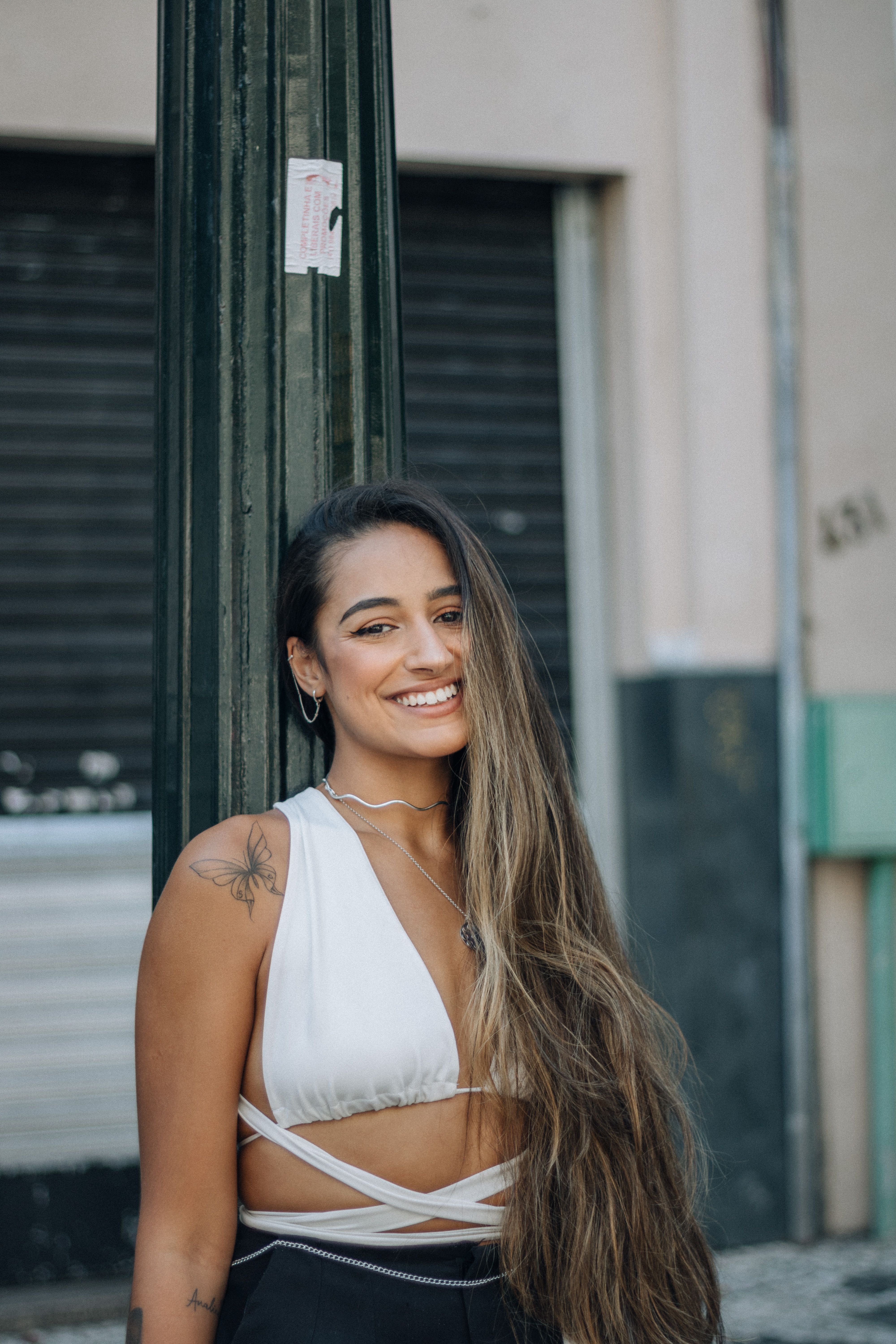 A woman standing confidently on a city street, showcasing a bright smile and casual urban style.