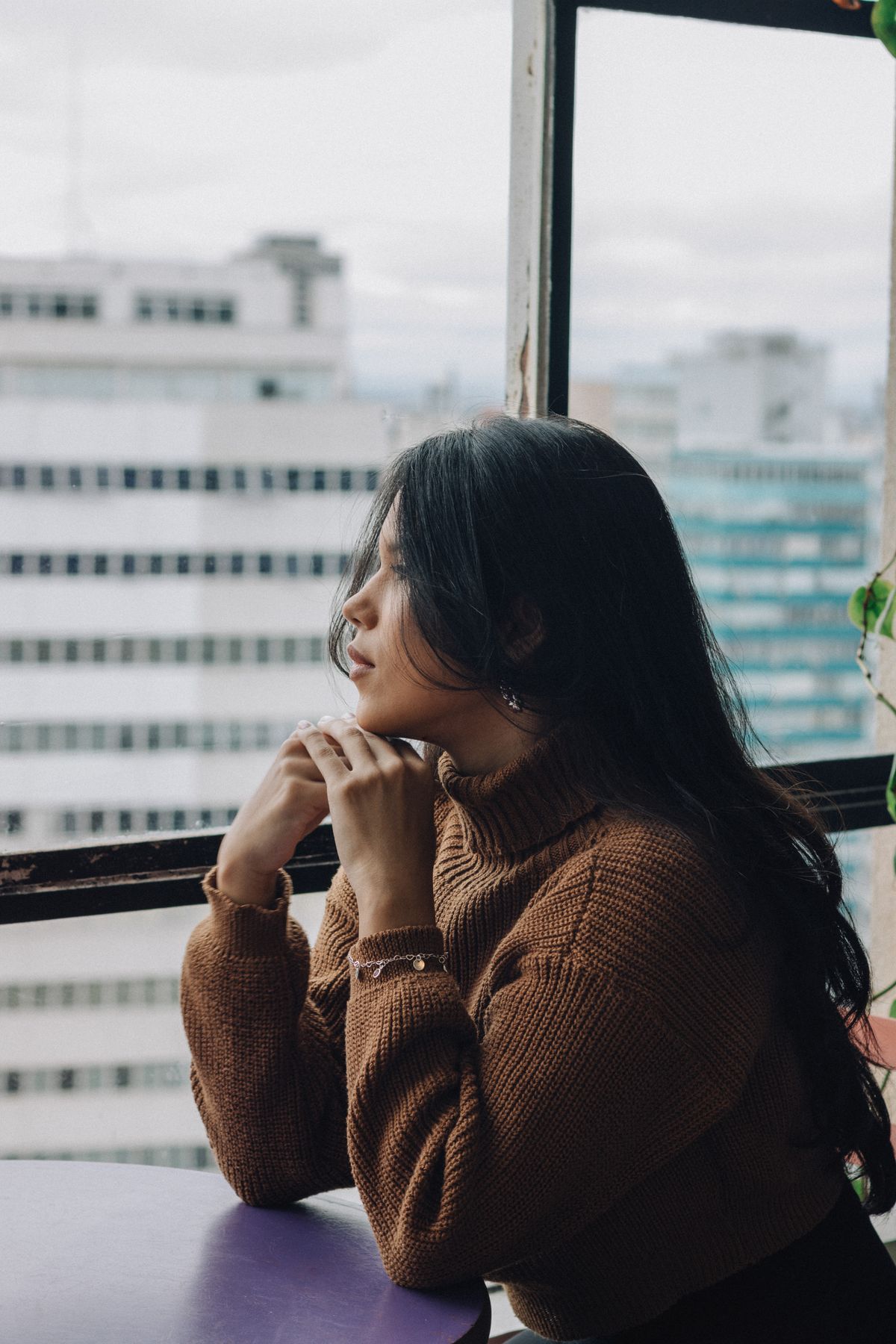 Người trẻ trầm ngâm nhìn ra cửa sổ thành phố