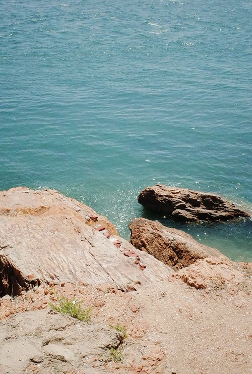 Free Peaceful seaside landscape with rocky cliffs and clear blue water under a bright sky. Stock Photo