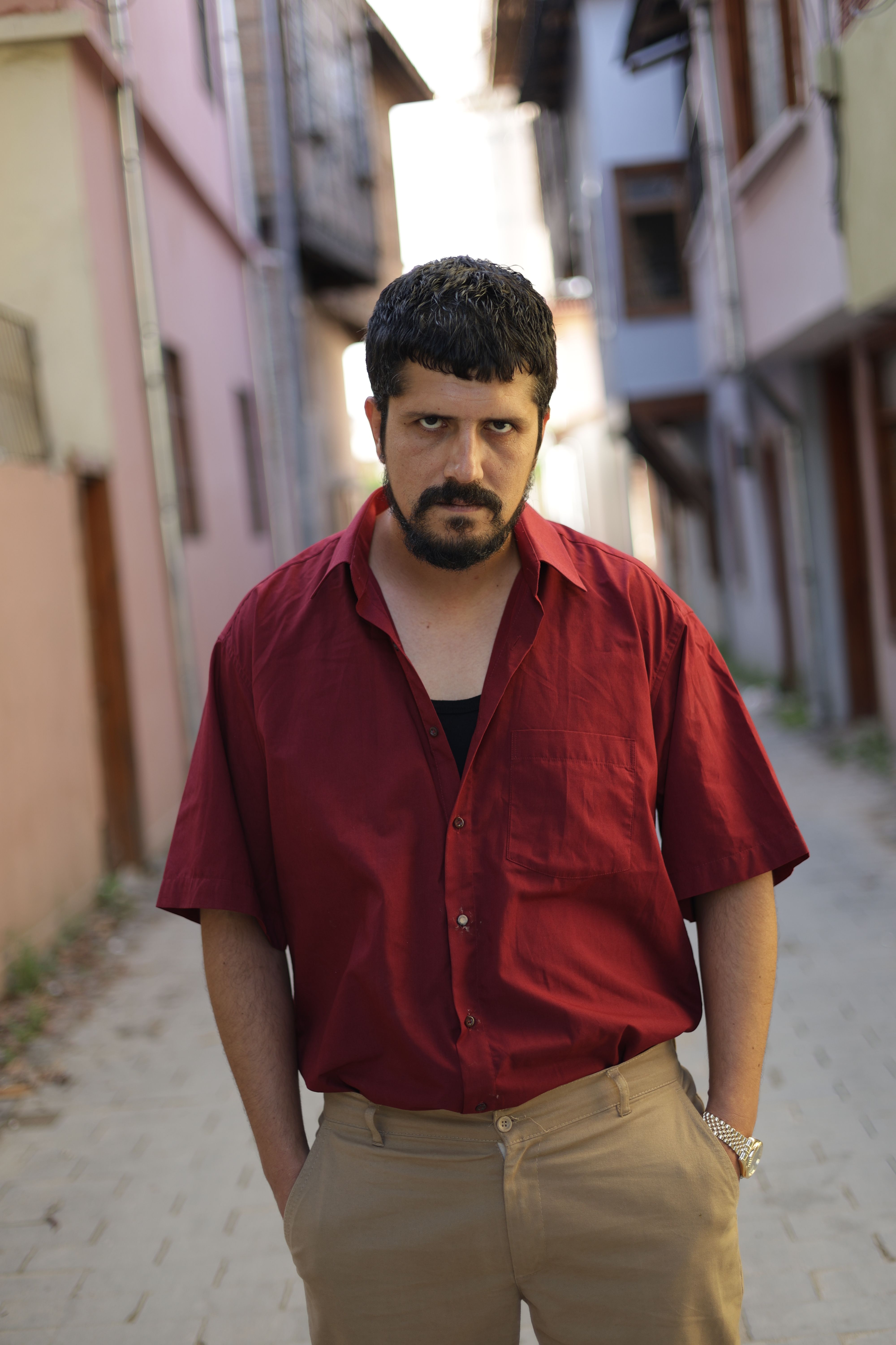 Serious man in a red shirt posing on a narrow street in Türkiye.