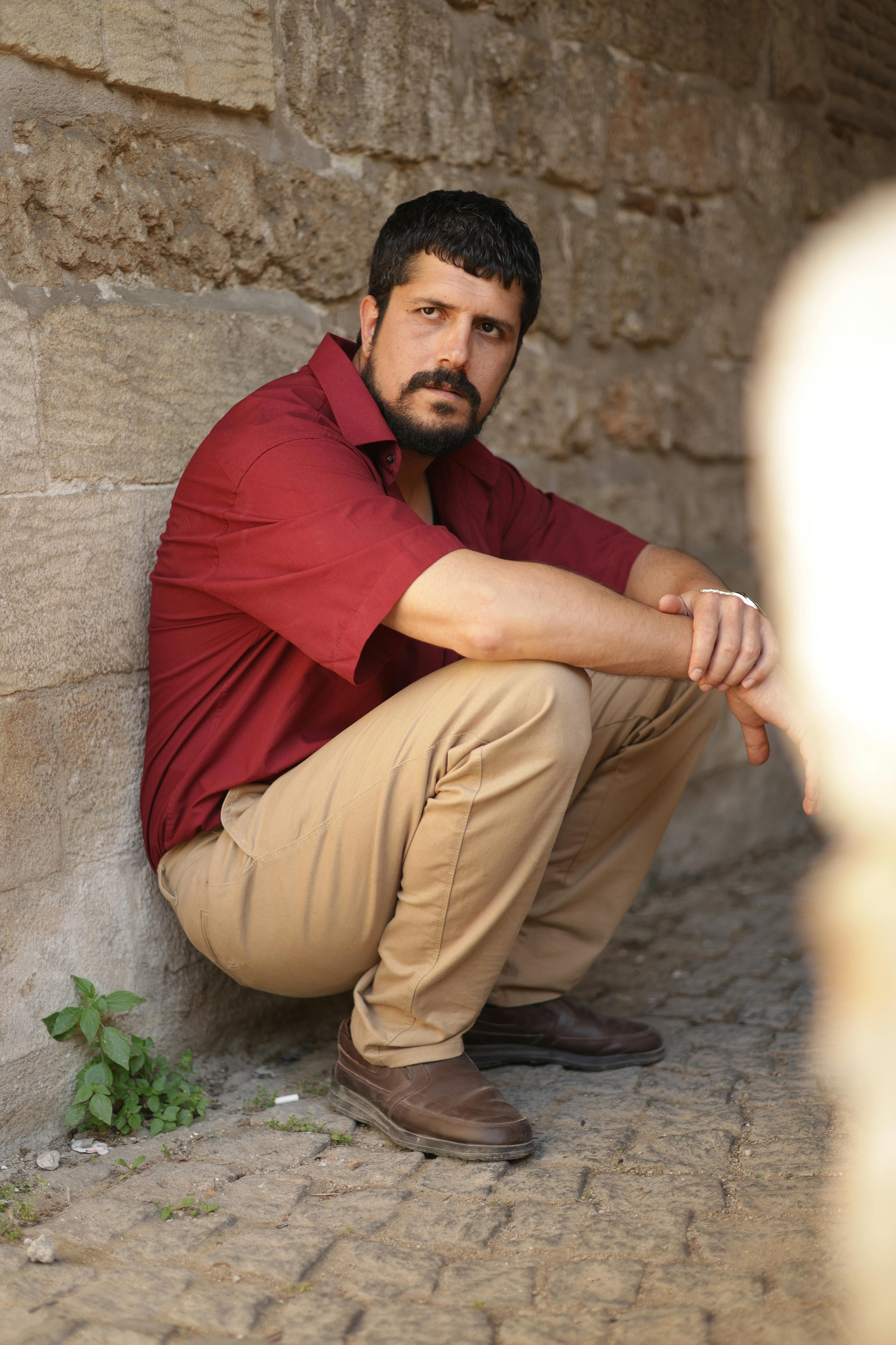 A man in casual attire poses in an alley in Türkiye. Daytime portrait.