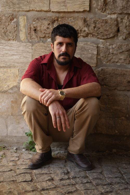 Free Portrait of a man in red shirt posing against a textured stone wall in Türkiye. Stock Photo