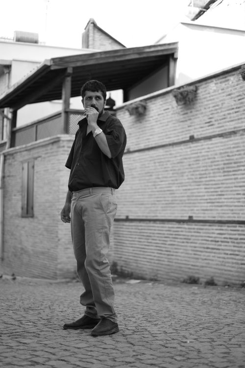 Free Monochrome photo of a man posing outdoors against a rustic wall in Türkiye. Stock Photo