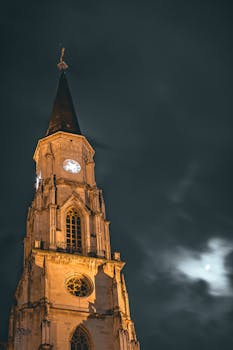 雄伟的哥特式钟楼耸立在黑暗、多云的夜空下