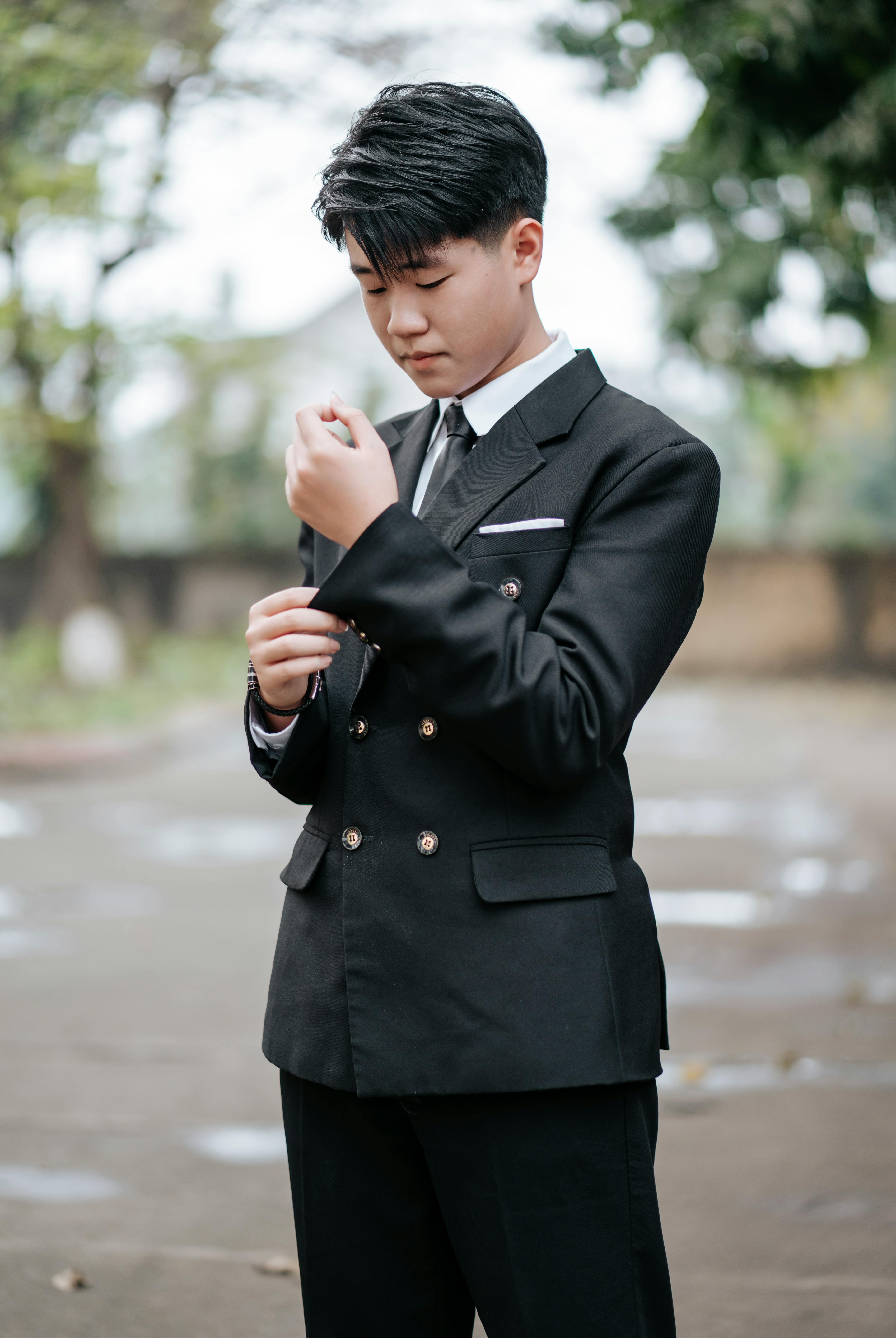 Teenager in Elegant Suit Adjusting Cufflinks Outdoors