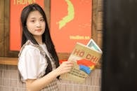 Young Woman Holding Book in Front of Map Poster