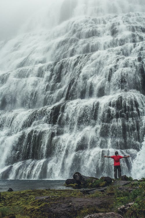 A Person in Red Shirt Standing in Front of the Waterfalls