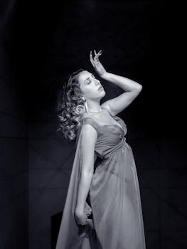 Black and white portrait of a woman posing elegantly indoors.