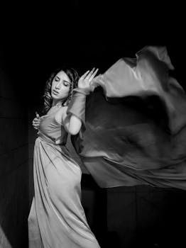 Elegant black and white photo of a woman posing gracefully in a flowing dress.