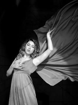 Striking black and white portrait featuring a woman in a flowing dress, showcasing grace and elegance.