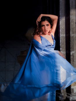 Portrait of a stylish woman in a flowing blue dress, showcasing elegance and grace.