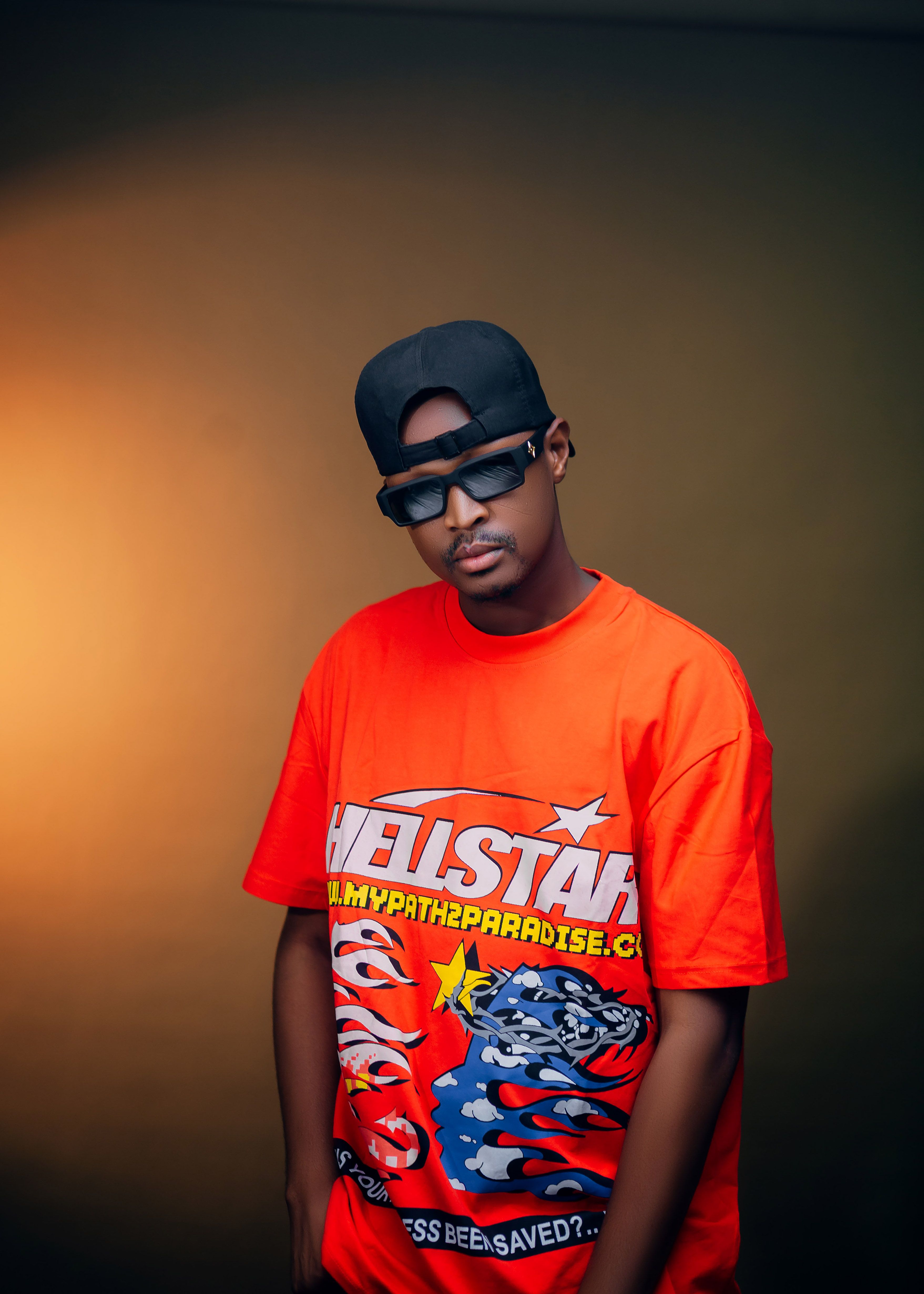Young man wearing sunglasses and a red graphic tee poses with confidence indoors.