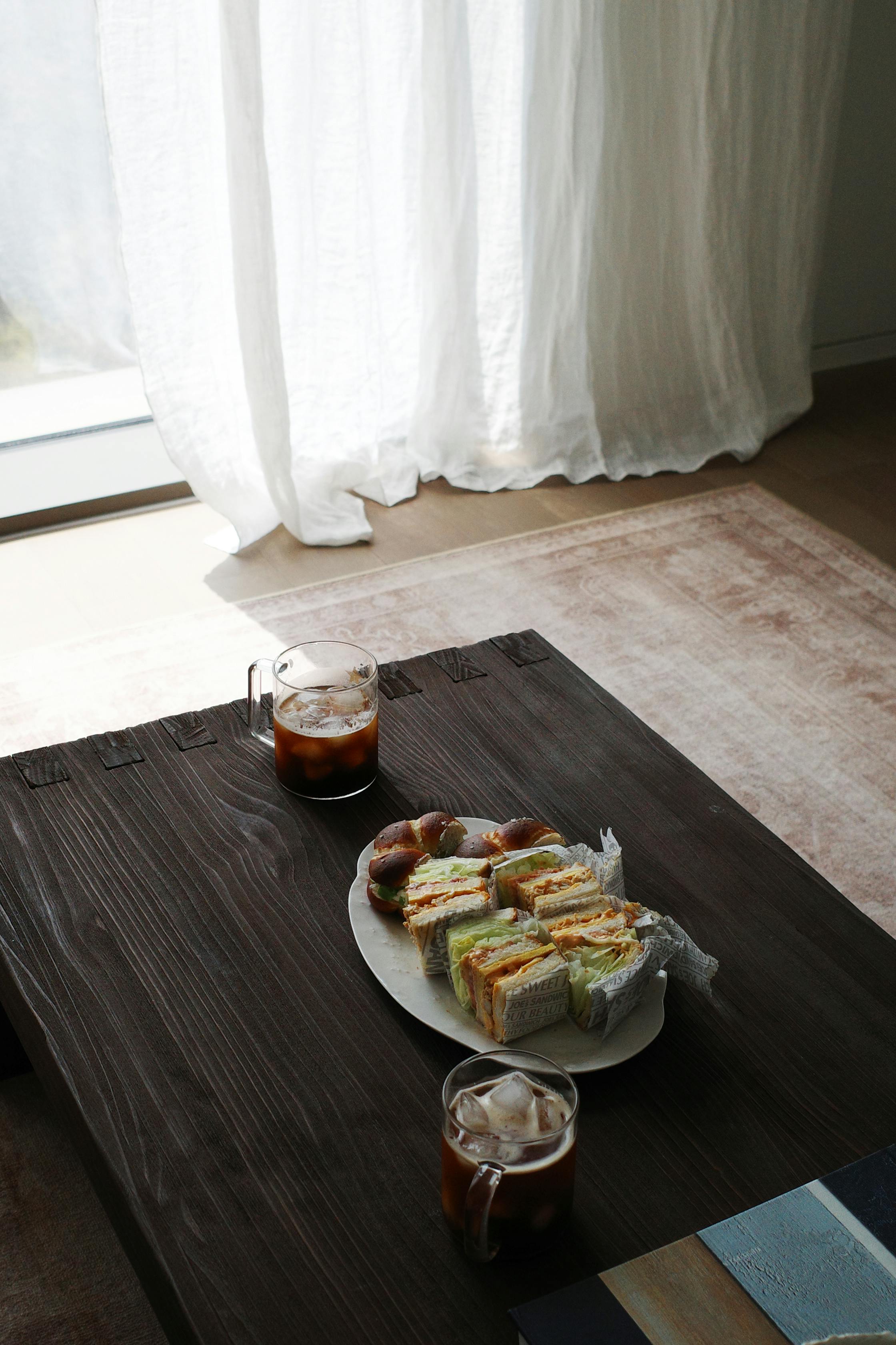 Relaxing indoor scene with sandwiches and iced coffee on a rustic table, perfect for a homely brunch.