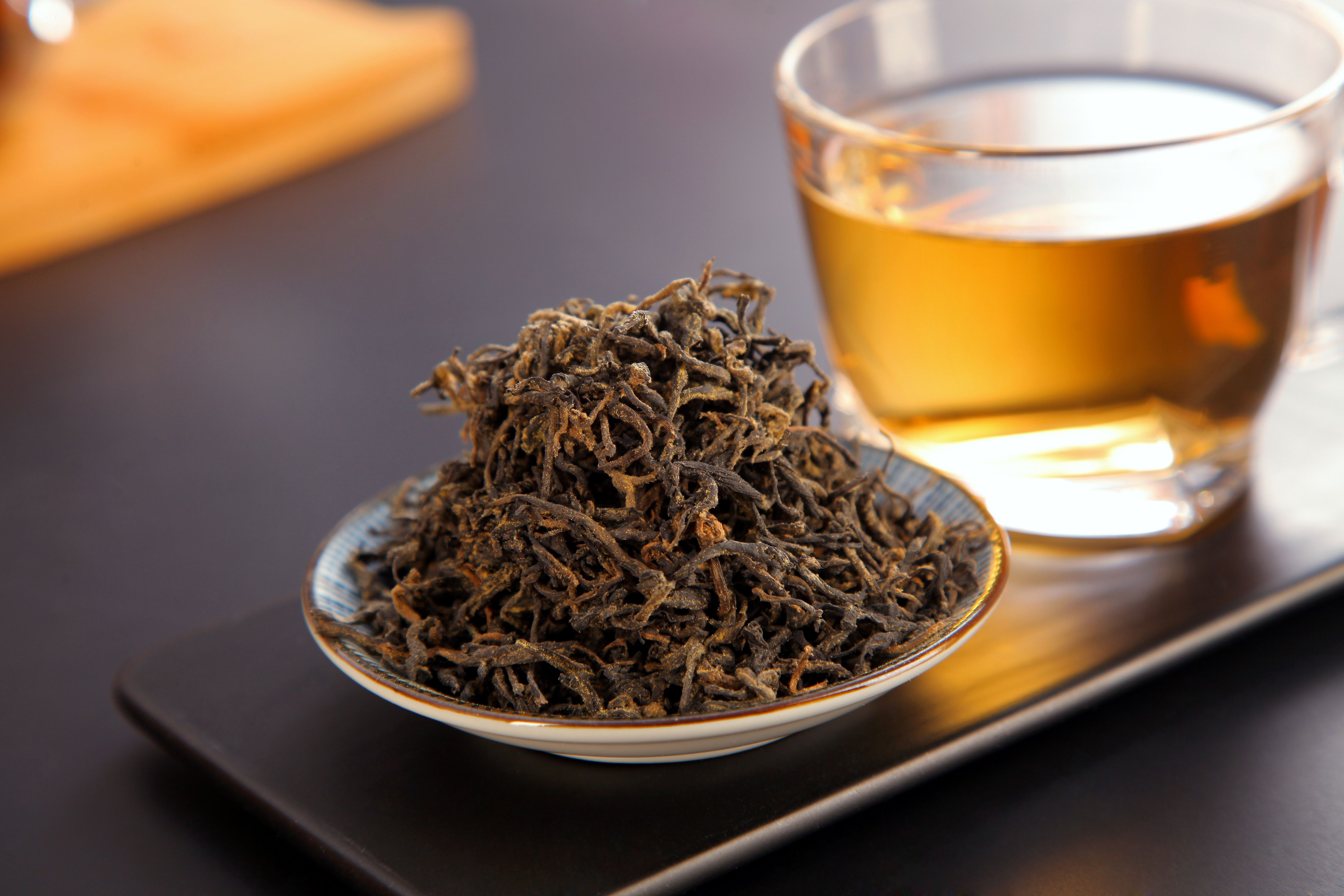 A close-up of loose leaf black tea beside a brewed cup, showcasing rich texture and warmth.