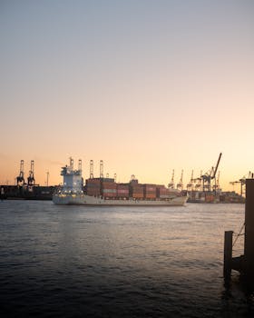 A container ship sails through Hamburg harbor at sunset, capturing industrial beauty.