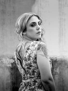 Black and white portrait of a tattooed woman with a confident pose, taken outdoors.