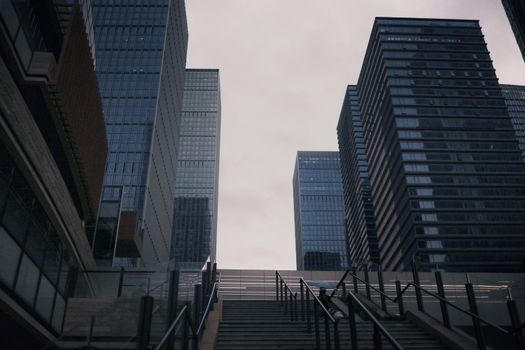 View of modern skyscrapers upwards with urban stairs in foreground.