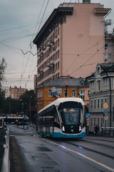 A sleek, modern tram travels down a wet street in Moscow, Russia during the early hours.