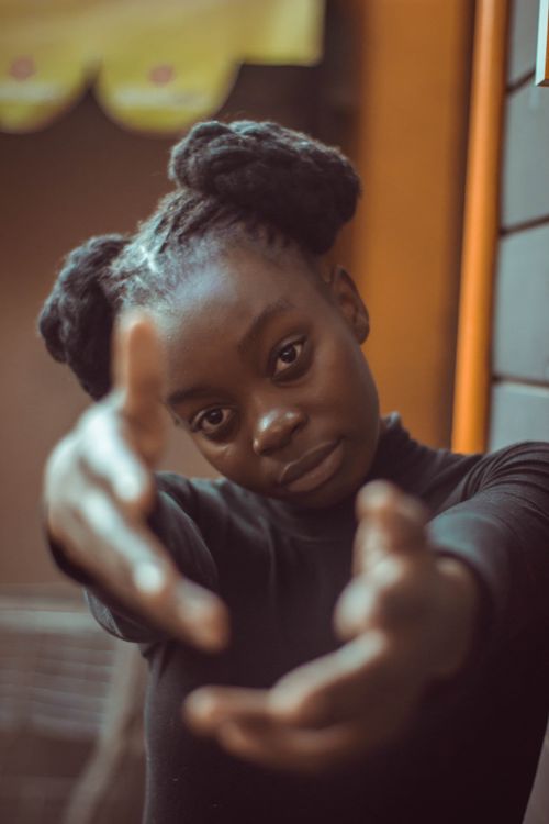 Free Close-up portrait of a young woman making a playful gesture, showcasing her hairstyle and fashion sense. Stock Photo