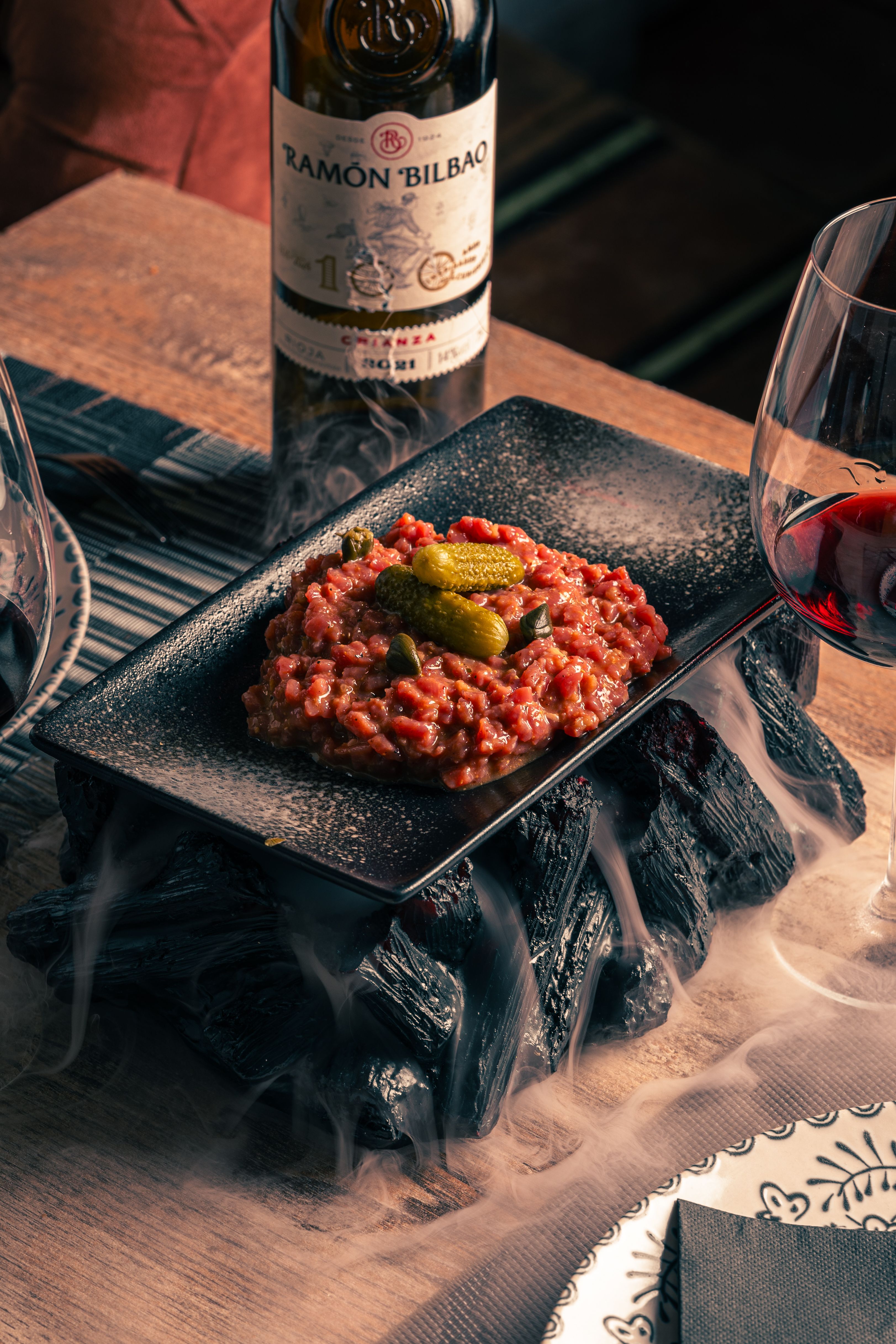 Elegant beef tartare with cucumbers served with red wine and Ramon Bilbao bottle.