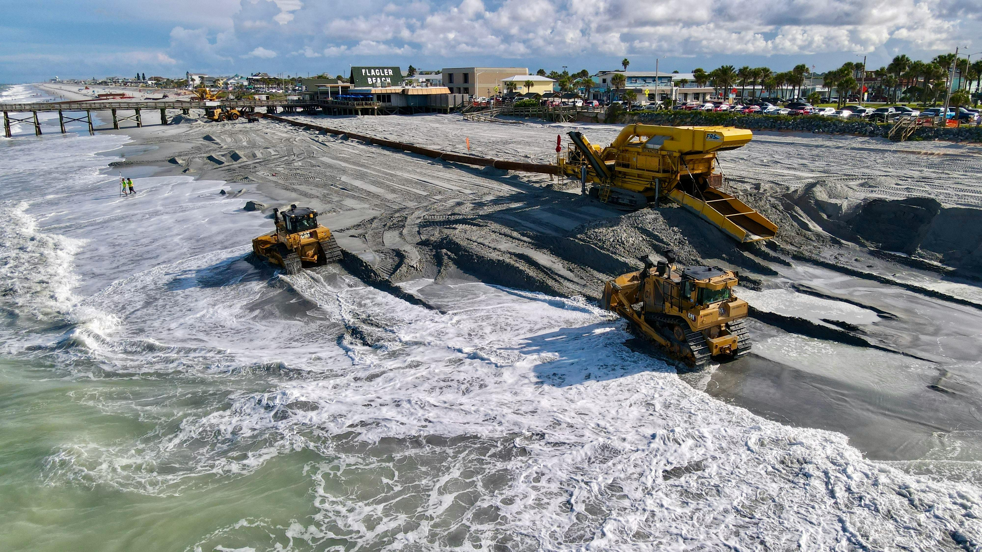 Heavy machinery working at Flagler Beach, showcasing beach restoration near the pier.