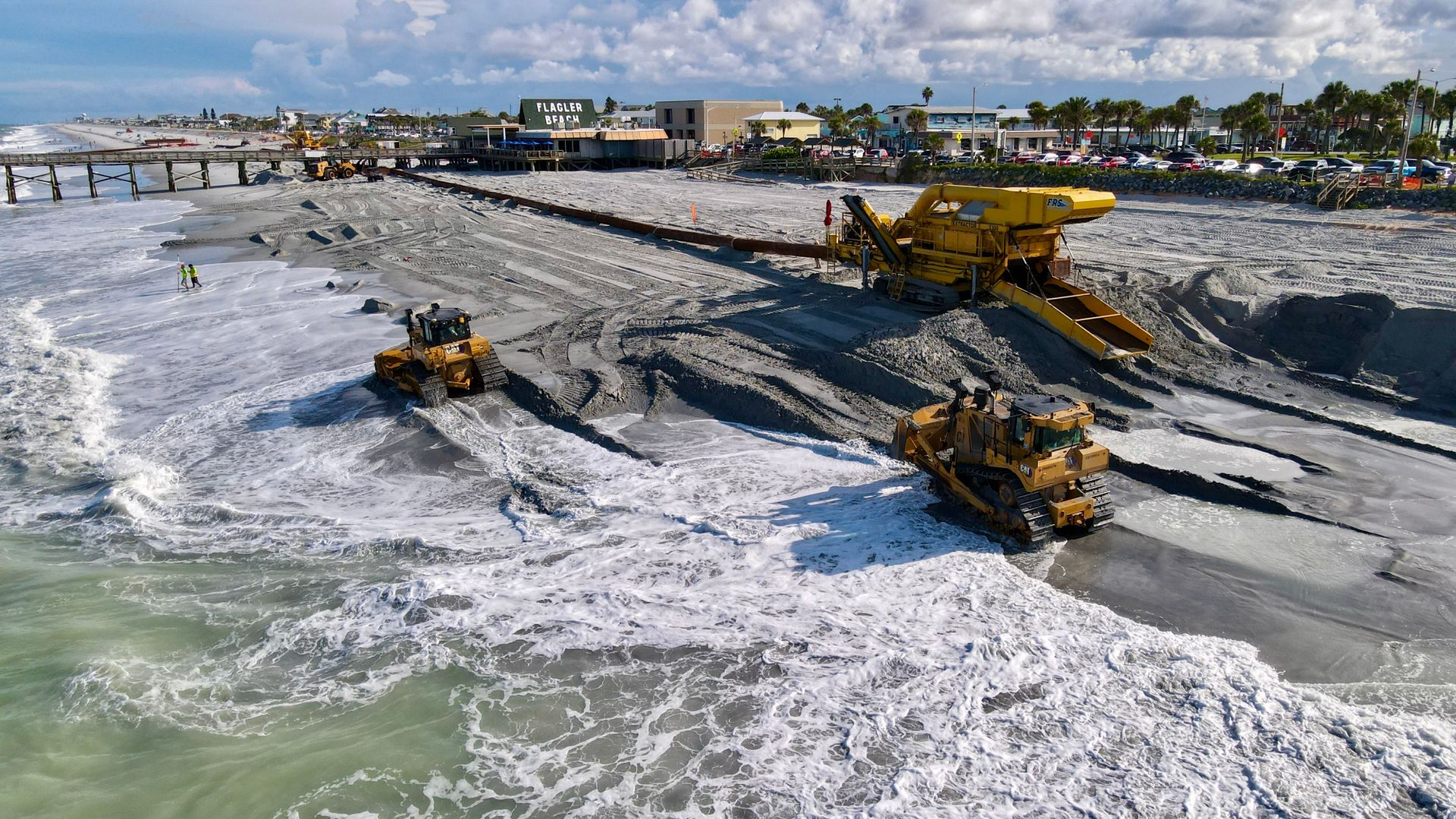 Heavy machinery working at Flagler Beach, showcasing beach restoration near the pier.
