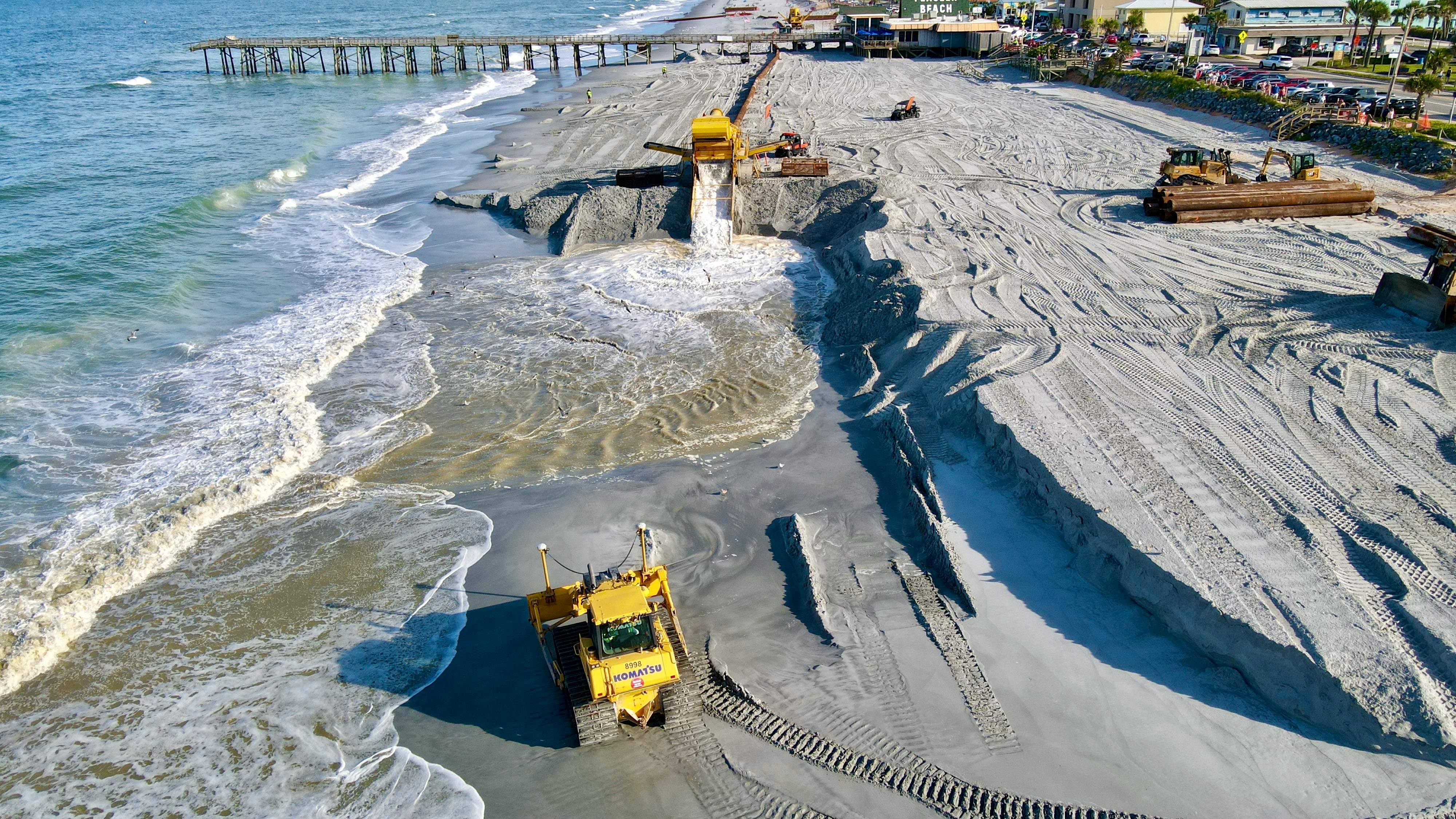 Free Aerial view of beach reclamation project with construction vehicles reshaping the coastline. Stock Photo