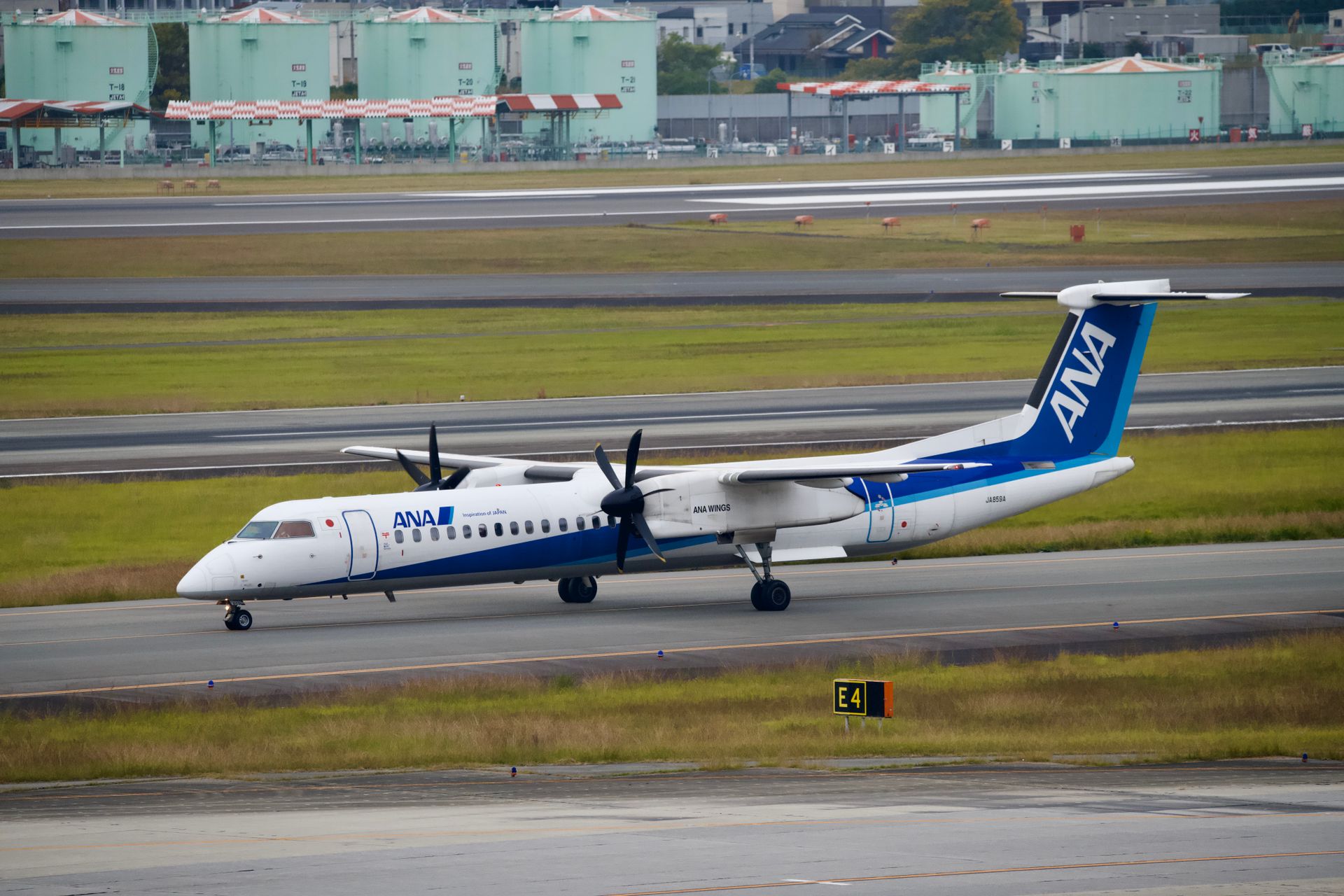 An ANA aircraft taxiing on the runway at a busy airport, showcasing aviation activity.